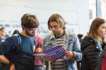 Students looking through a course guideline book at open day
