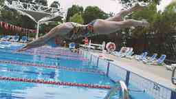 Female student dives into a pool at the open air Hawthorn Aquatic Centre