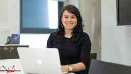 Swinburne student Diana sitting at a desk smiling with an Apple laptop in the upright position. 