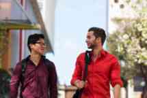 Two male students wearing red walk outside talking 