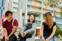Three international students sit outside in the Hawthorn campus gardens
