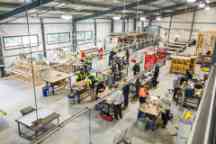An open, warehouse style classroom with plumbing students engaging in practical learning