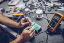 Repairman Checking Voltage With Digital Multimeter