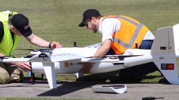 Two men working on the SHADE drone on the tarmac of an airport