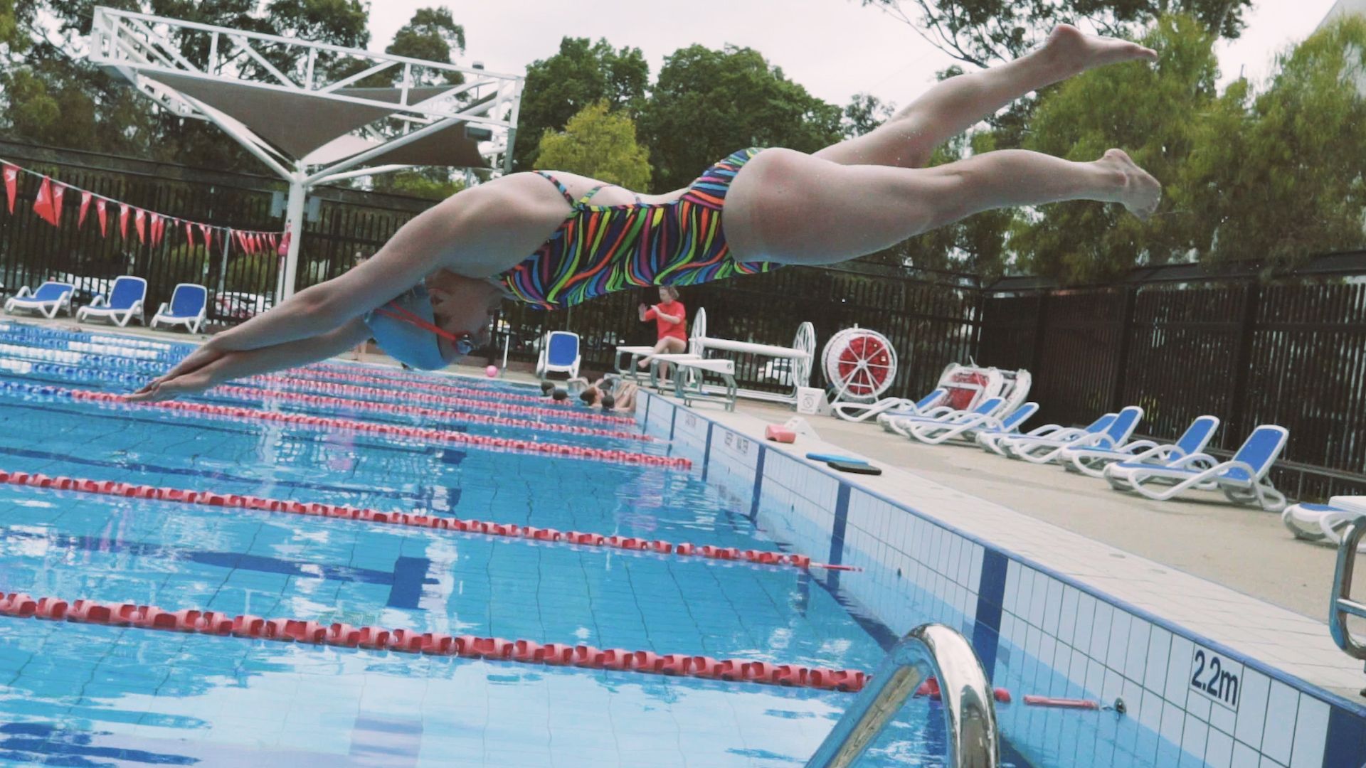 Female student dives into a pool at the open air Hawthorn Aquatic Centre