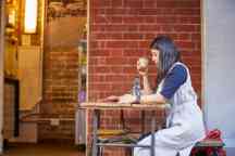 Young female student sits at a table drinking coffee and reading