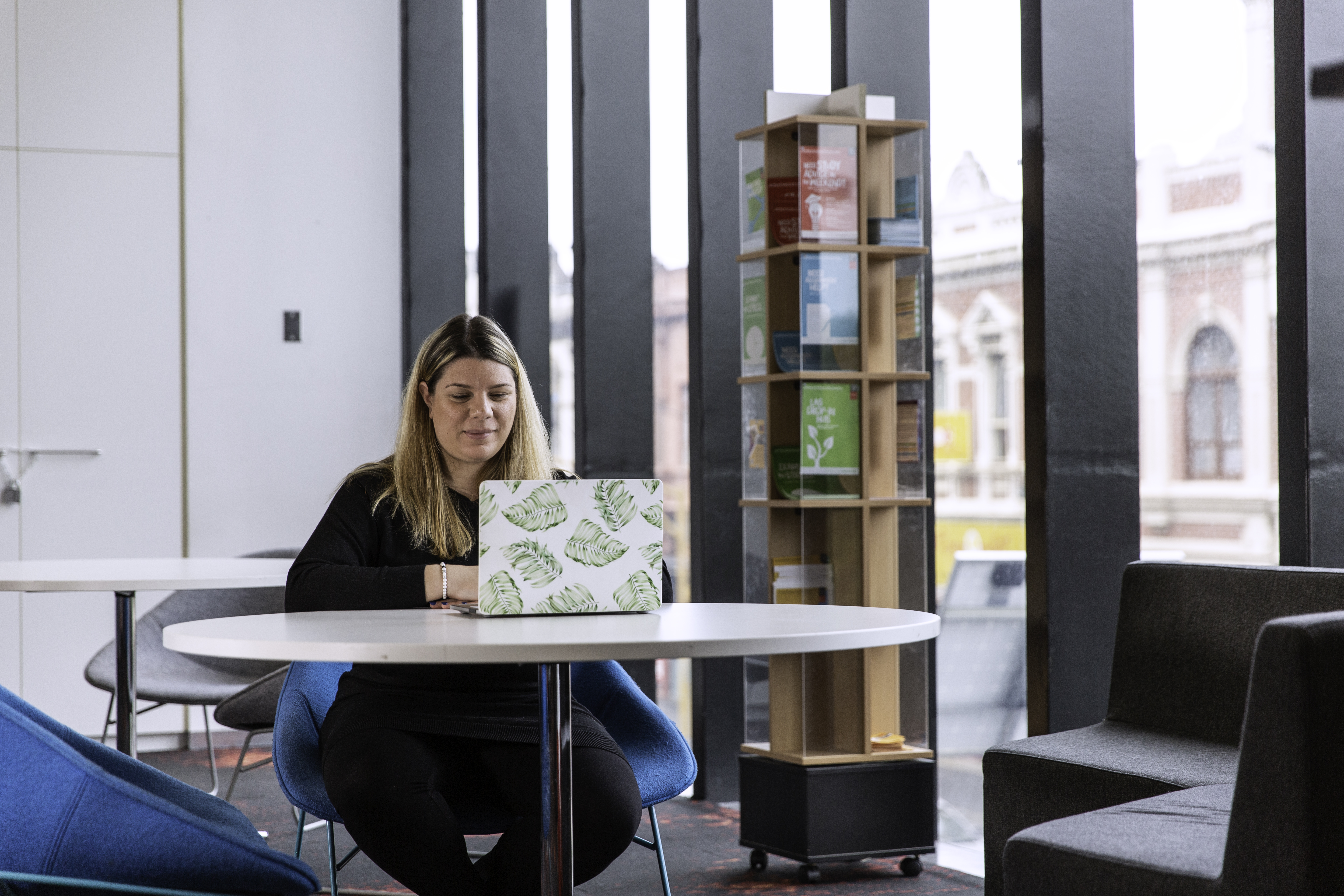 A Blonde woman wearing black, works at a laptop at one of Swinburne's various study spaces