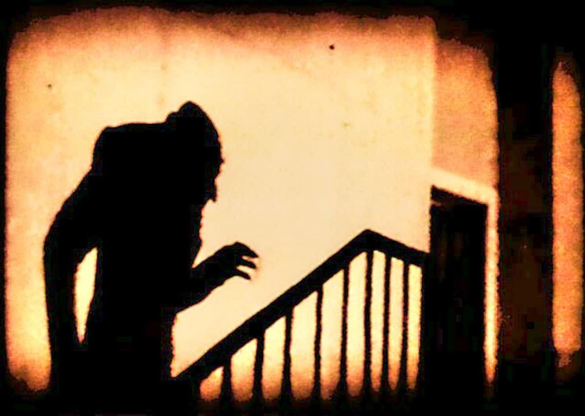 A shadow of a vampire against a wall as they walk up stairs