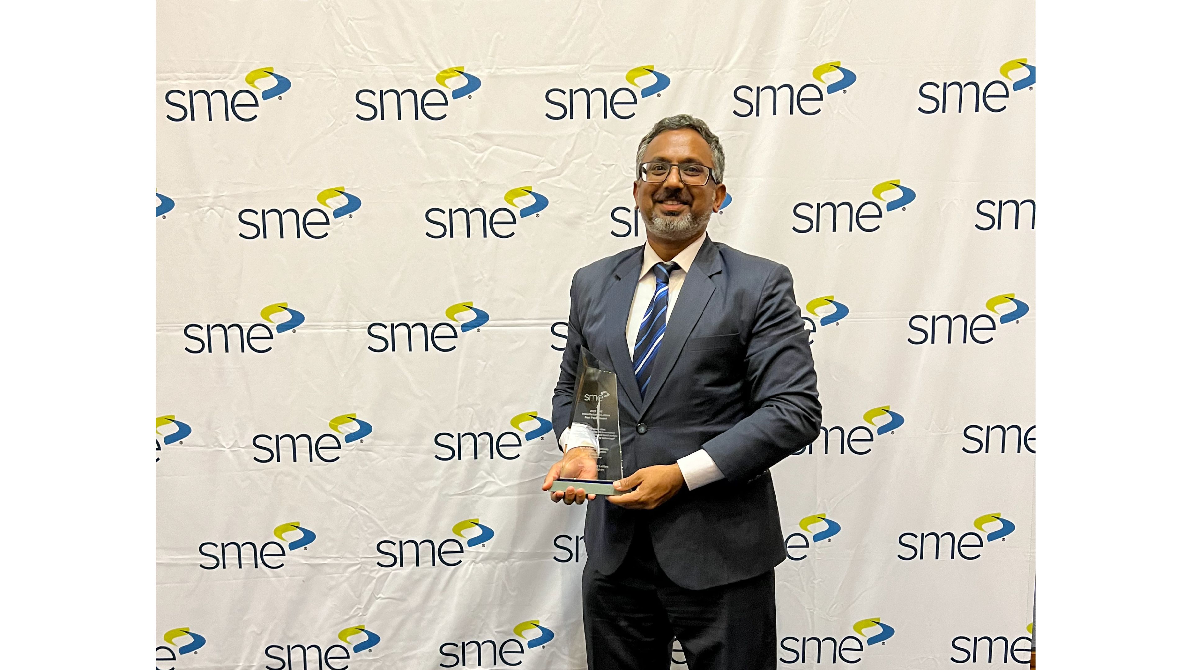 Professor Suresh Palanisamy is pictured in front of a media wall smiling and holding up a glass trophy for the latest Manufacturing Letters Best Paper Award from the Society of Manufacturing Engineers 