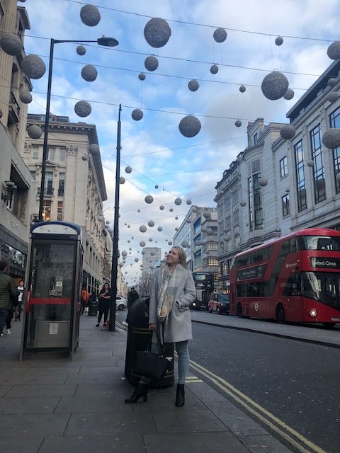 Female standing in a busy London street with Christmas decorations overhead