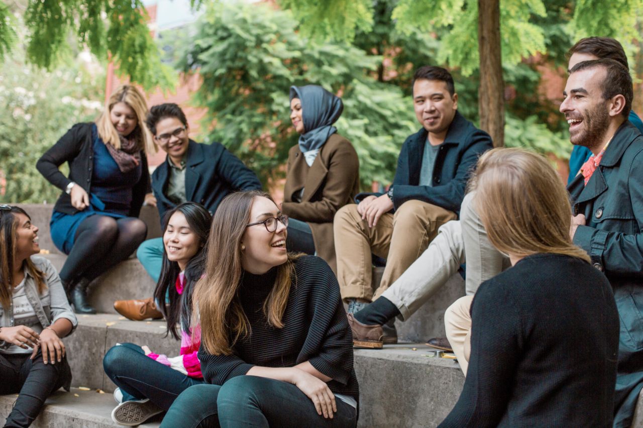 Group of students socialising outside on steps laughing