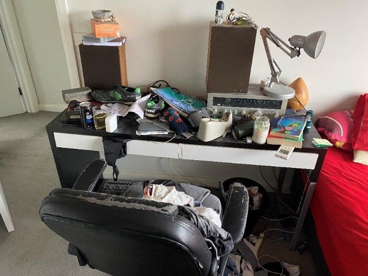 Spencer’s desk, littered with miscellaneous personal items such as shoes, socks, deodorant cans and a defunct antique radio.